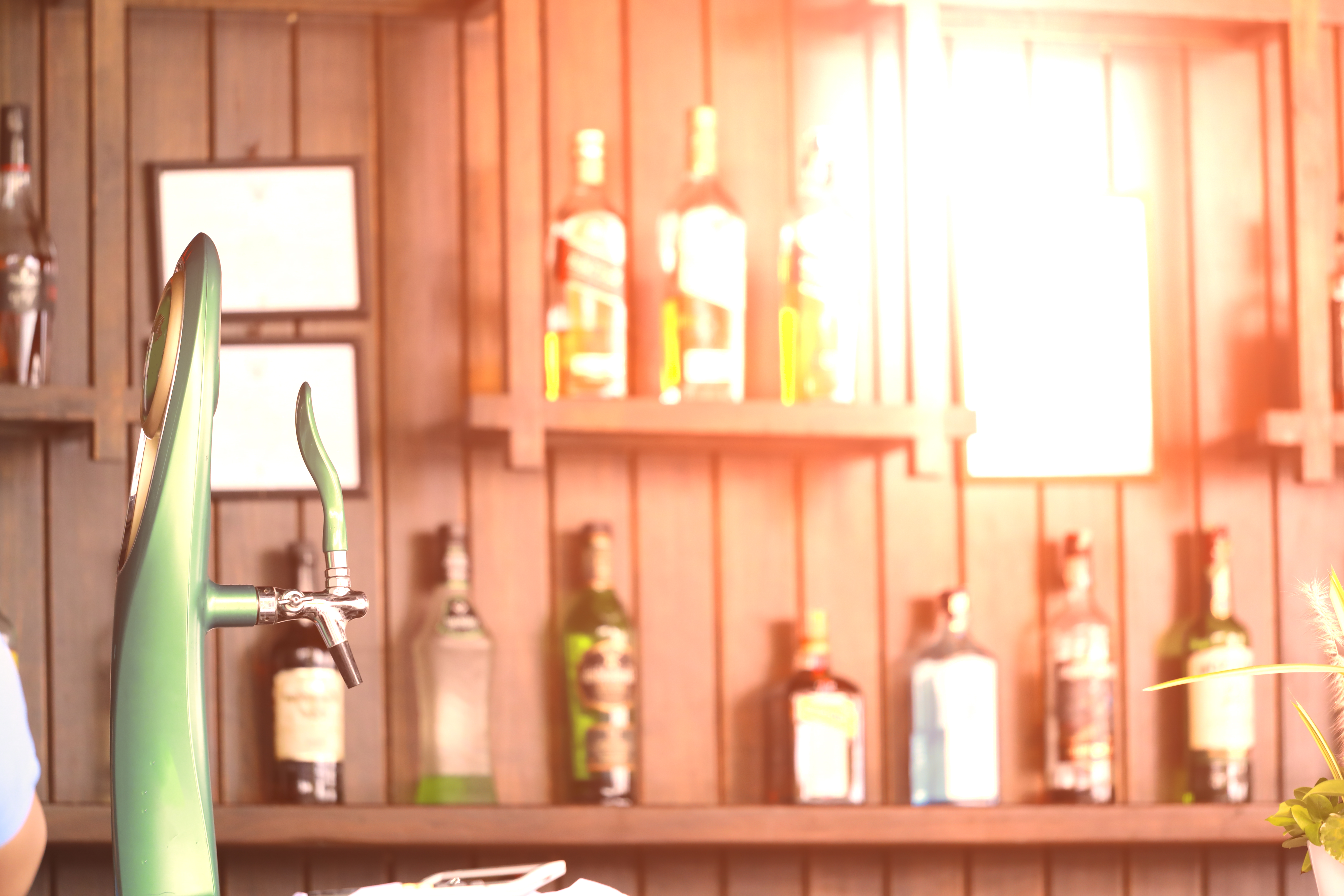 Wooden bar with cocktail bottles and a beer pump